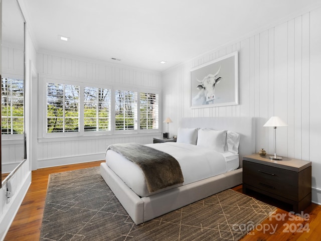 bedroom featuring visible vents, crown molding, and wood finished floors