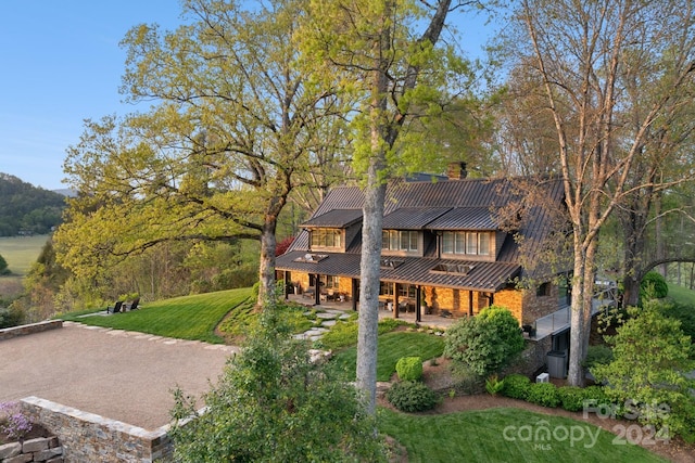 exterior space featuring a standing seam roof, a front yard, a patio area, and metal roof