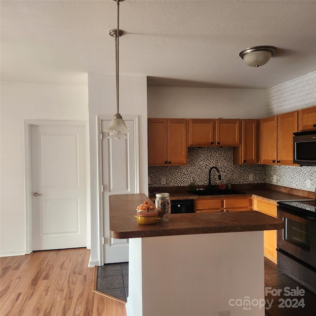 kitchen featuring pendant lighting, backsplash, sink, electric range, and a textured ceiling