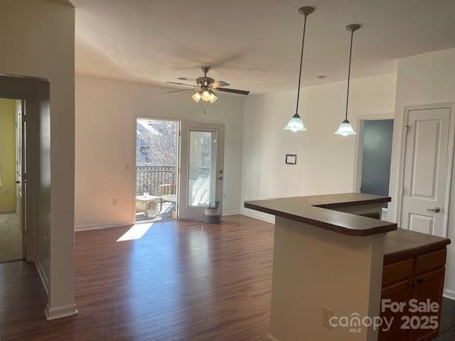 kitchen featuring a ceiling fan, baseboards, dark countertops, and dark wood-style floors
