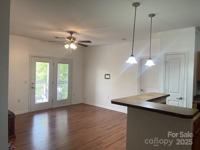 interior space featuring dark countertops, baseboards, a ceiling fan, and wood finished floors