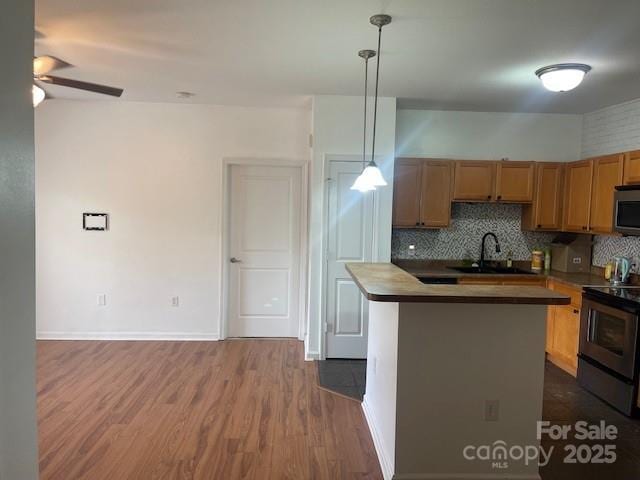 kitchen with tasteful backsplash, a sink, ceiling fan, appliances with stainless steel finishes, and dark wood-style floors