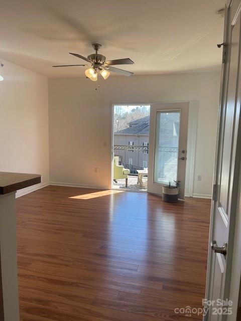 unfurnished room with baseboards, wood finished floors, and ceiling fan
