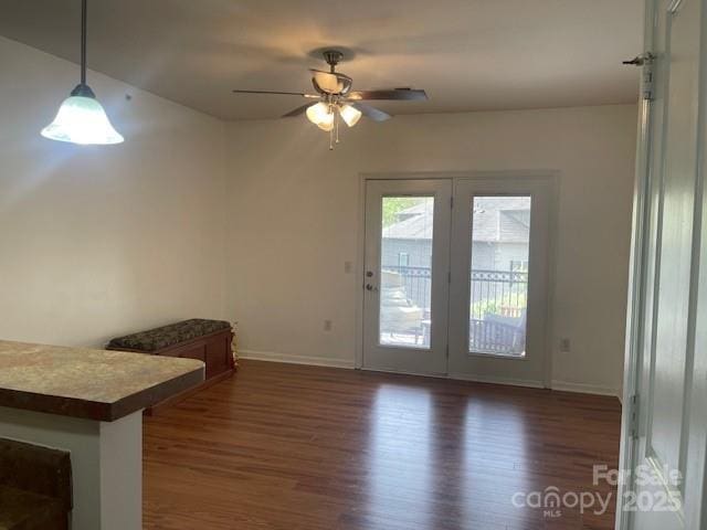 doorway featuring a ceiling fan, baseboards, and dark wood-style flooring