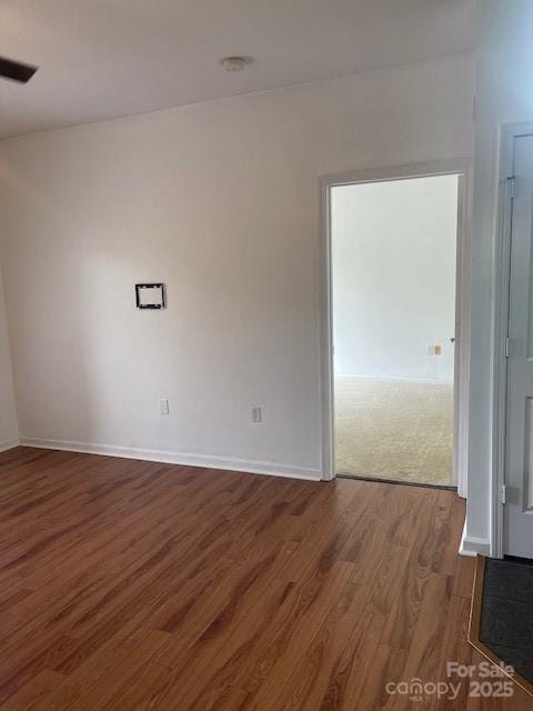 unfurnished room featuring baseboards and dark wood-type flooring