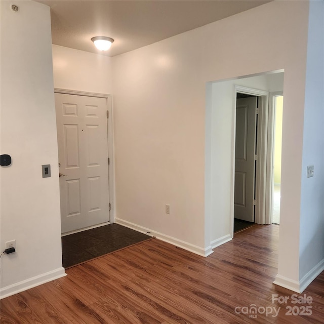 unfurnished room with baseboards and dark wood-style floors