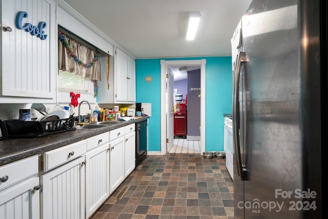 kitchen featuring dishwasher, sink, white range, white cabinets, and stainless steel fridge