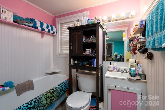 bathroom with a tub, toilet, vanity, and ornamental molding