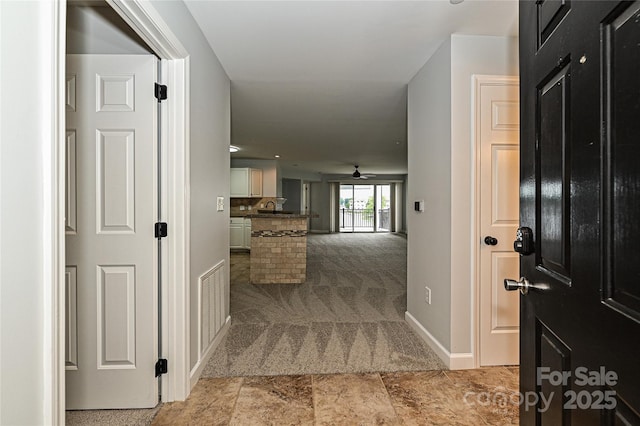 hall with light colored carpet and sink