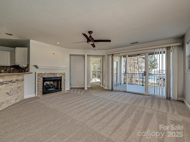 unfurnished living room featuring a fireplace, light colored carpet, ceiling fan, and sink