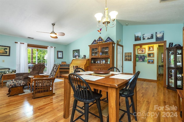 dining space with ceiling fan with notable chandelier, lofted ceiling, light hardwood / wood-style floors, and a textured ceiling