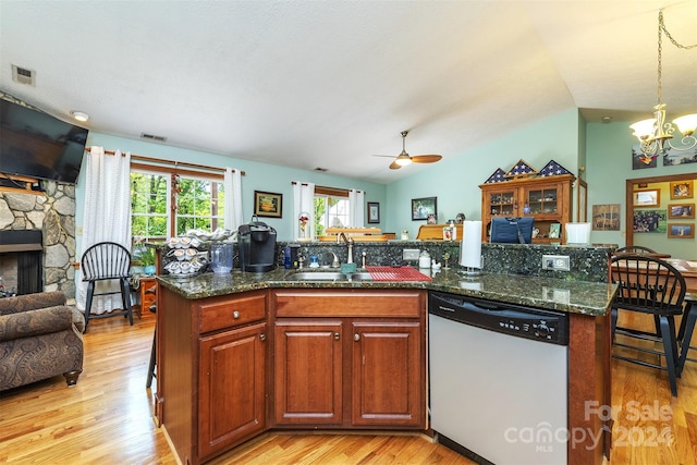 kitchen featuring a fireplace, sink, vaulted ceiling, light hardwood / wood-style floors, and dishwasher