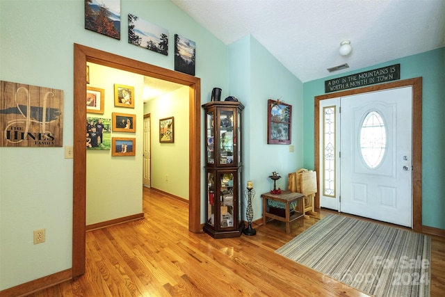 foyer entrance featuring vaulted ceiling and hardwood / wood-style floors