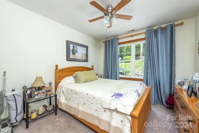 bedroom with a textured ceiling, ceiling fan, and carpet