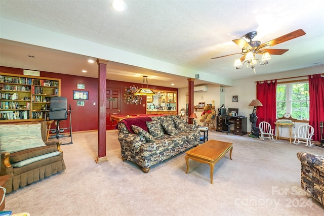 carpeted living room with a textured ceiling, ceiling fan, a wall mounted air conditioner, and decorative columns