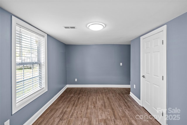 spare room featuring dark hardwood / wood-style flooring and plenty of natural light