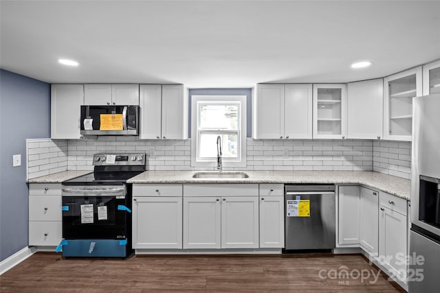 kitchen with white cabinets, sink, light stone countertops, appliances with stainless steel finishes, and dark hardwood / wood-style flooring