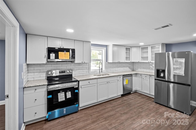 kitchen featuring sink, dark hardwood / wood-style flooring, backsplash, white cabinets, and appliances with stainless steel finishes