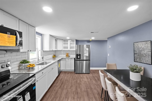 kitchen with backsplash, sink, dark hardwood / wood-style floors, white cabinetry, and stainless steel appliances