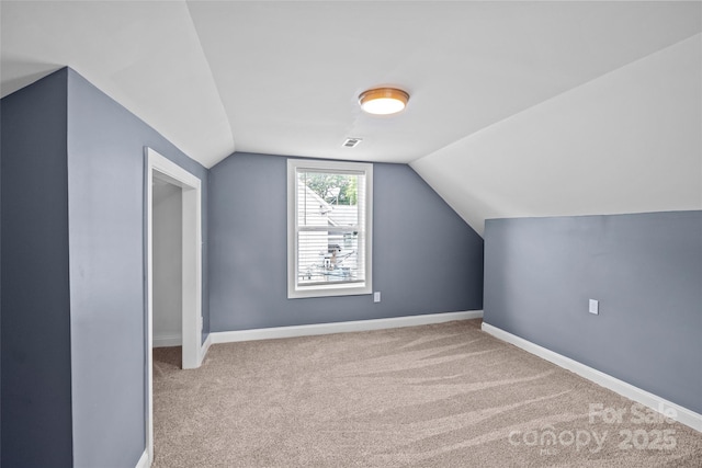 bonus room with light colored carpet and vaulted ceiling