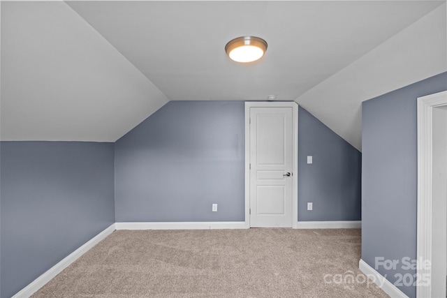 bonus room with light colored carpet and vaulted ceiling