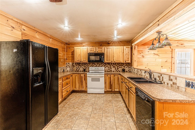 kitchen with decorative light fixtures, sink, black appliances, and wooden walls