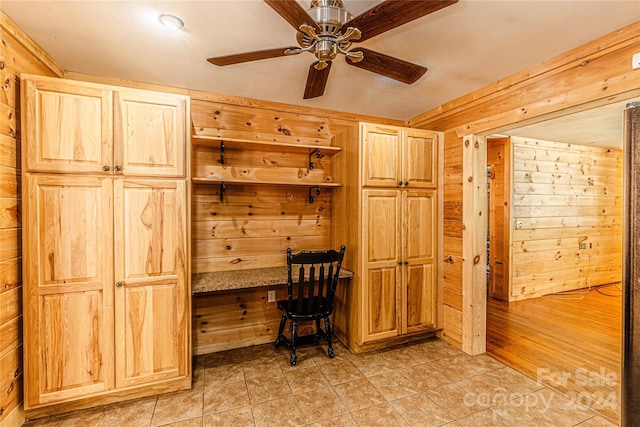 unfurnished office with ceiling fan and wooden walls