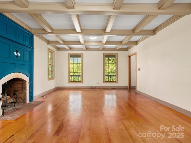 unfurnished living room with coffered ceiling, a tiled fireplace, light hardwood / wood-style flooring, and beam ceiling