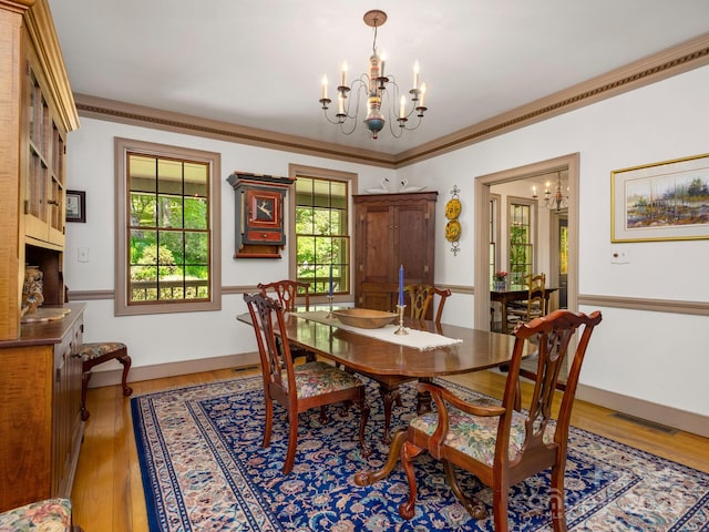 dining area featuring hardwood / wood-style flooring, ornamental molding, and a chandelier