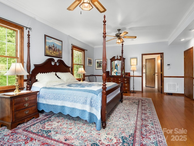 bedroom featuring hardwood / wood-style floors, ceiling fan, ornamental molding, and multiple windows