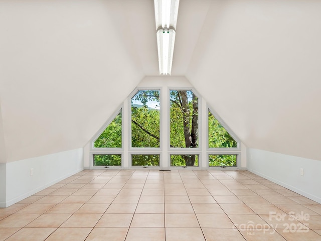 additional living space with vaulted ceiling and light tile patterned floors