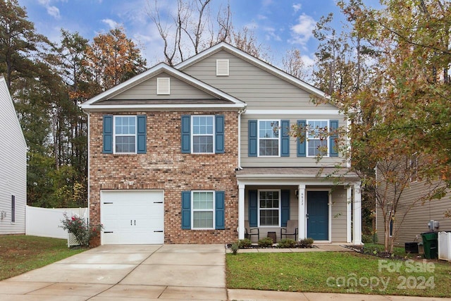 view of front of property with a garage, covered porch, and a front yard