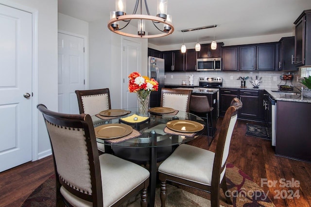 dining space featuring dark wood-type flooring, sink, and an inviting chandelier