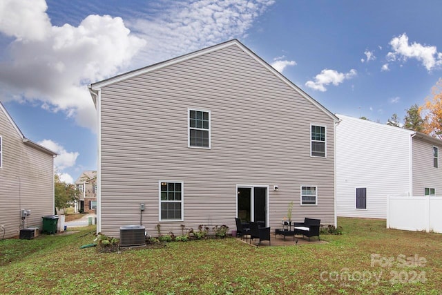 rear view of property featuring a lawn, central AC, and a patio area