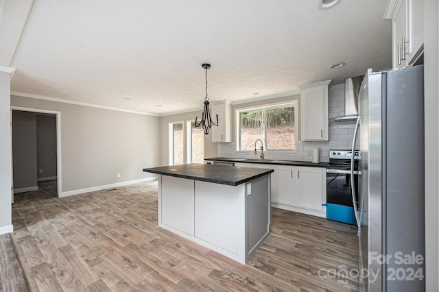 kitchen featuring a kitchen island, stainless steel appliances, wall chimney exhaust hood, white cabinets, and hardwood / wood-style flooring