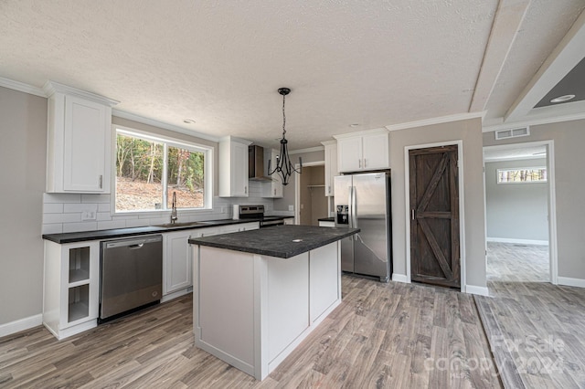 kitchen with a center island, decorative light fixtures, white cabinets, and stainless steel appliances