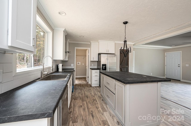 kitchen featuring sink, a kitchen island, hardwood / wood-style floors, white cabinetry, and stainless steel fridge