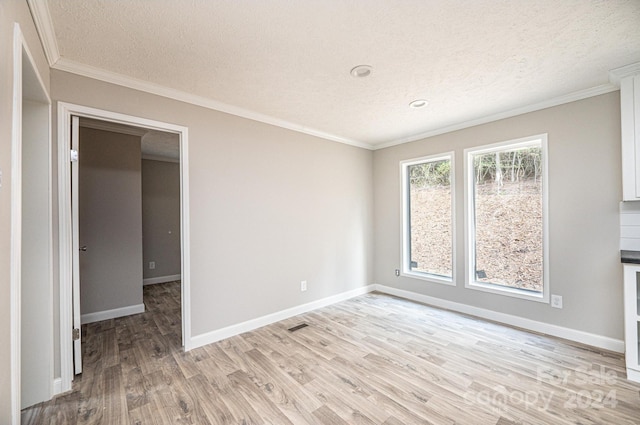 empty room with light hardwood / wood-style floors, crown molding, and a textured ceiling