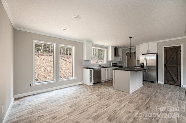 kitchen with white cabinets, appliances with stainless steel finishes, light wood-type flooring, and hanging light fixtures