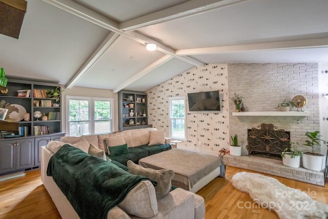 living room with lofted ceiling with beams, light wood-type flooring, and a fireplace