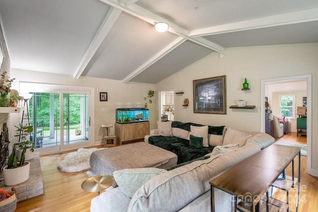 living room featuring hardwood / wood-style floors, lofted ceiling with beams, and a brick fireplace