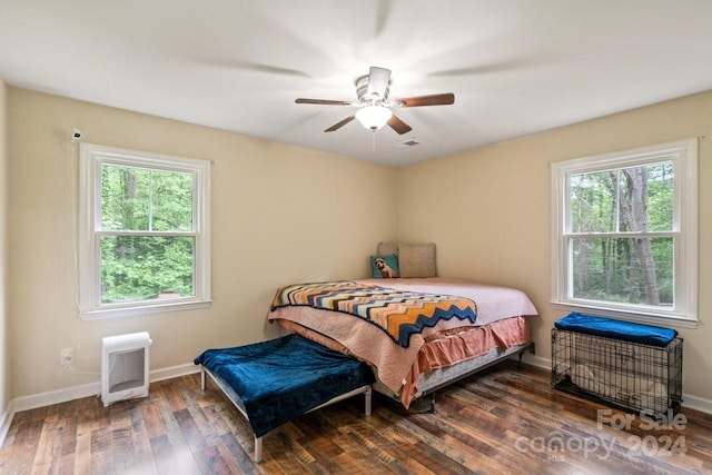 bedroom with multiple windows, heating unit, ceiling fan, and dark wood-type flooring