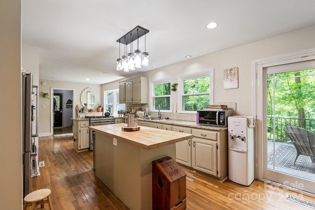 kitchen with a center island, sink, hardwood / wood-style flooring, decorative light fixtures, and stainless steel refrigerator