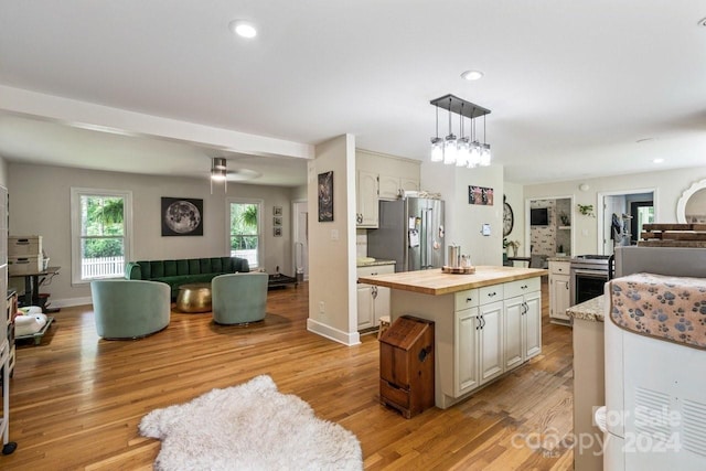 kitchen featuring light hardwood / wood-style floors, decorative light fixtures, a kitchen island, white cabinetry, and stainless steel appliances