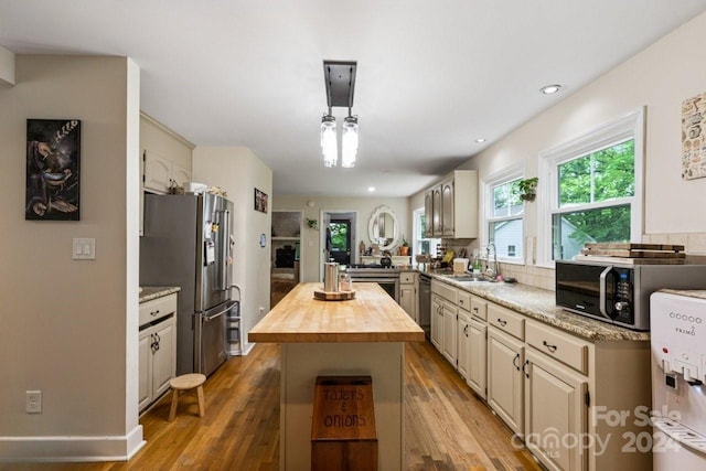 kitchen featuring wood counters, sink, appliances with stainless steel finishes, a kitchen island, and wood-type flooring