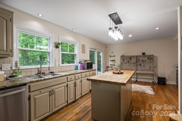 kitchen featuring wooden counters, sink, decorative light fixtures, dishwasher, and a center island