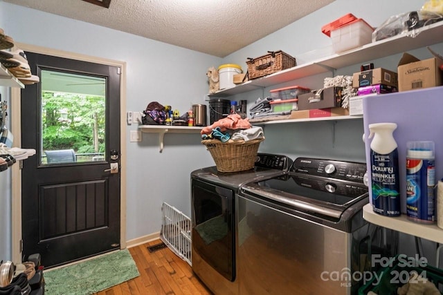 clothes washing area with a textured ceiling, light hardwood / wood-style floors, and washer and clothes dryer