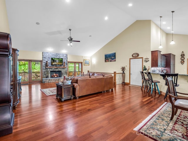 living room featuring a stone fireplace, high vaulted ceiling, dark hardwood / wood-style flooring, and ceiling fan