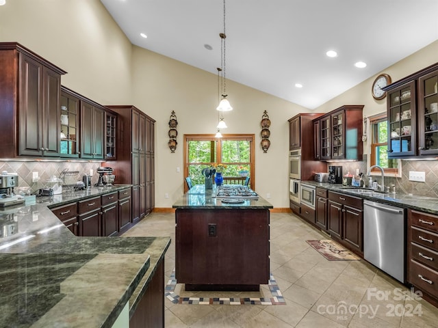 kitchen with decorative light fixtures, a kitchen island, backsplash, stainless steel appliances, and sink