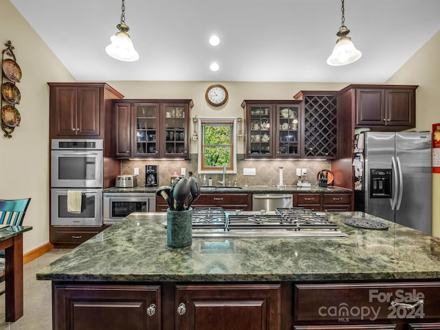 kitchen featuring light tile flooring, backsplash, appliances with stainless steel finishes, sink, and an island with sink